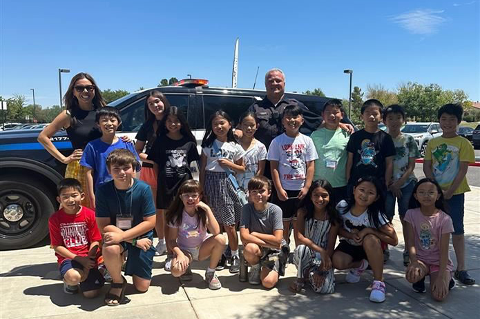 Image of police officer standing in a group shot with kids and teacher
